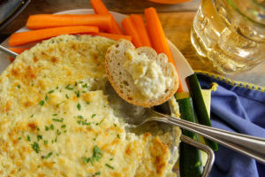 Hot Artichoke Dip in a serving bowl with spoon dipping into it