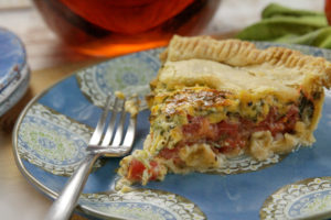 A wedge shaped slice of Deep Summer Tomato Pie on a plate 