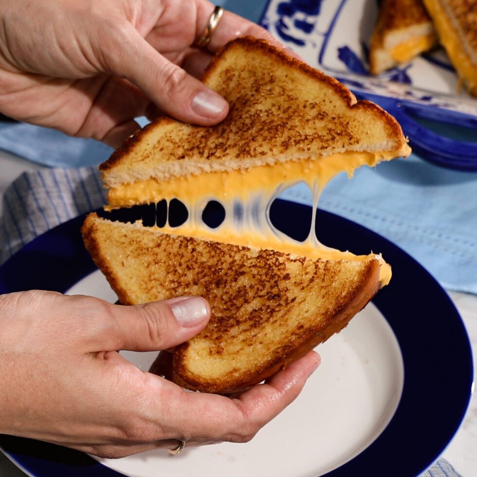 Two halves of a hot grilled cheese sandwich, pulled apart