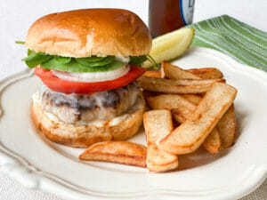 Turkey Burger dressed with lettuce, tomato and Blue Plate Mayonnaise served on a plate with french fries