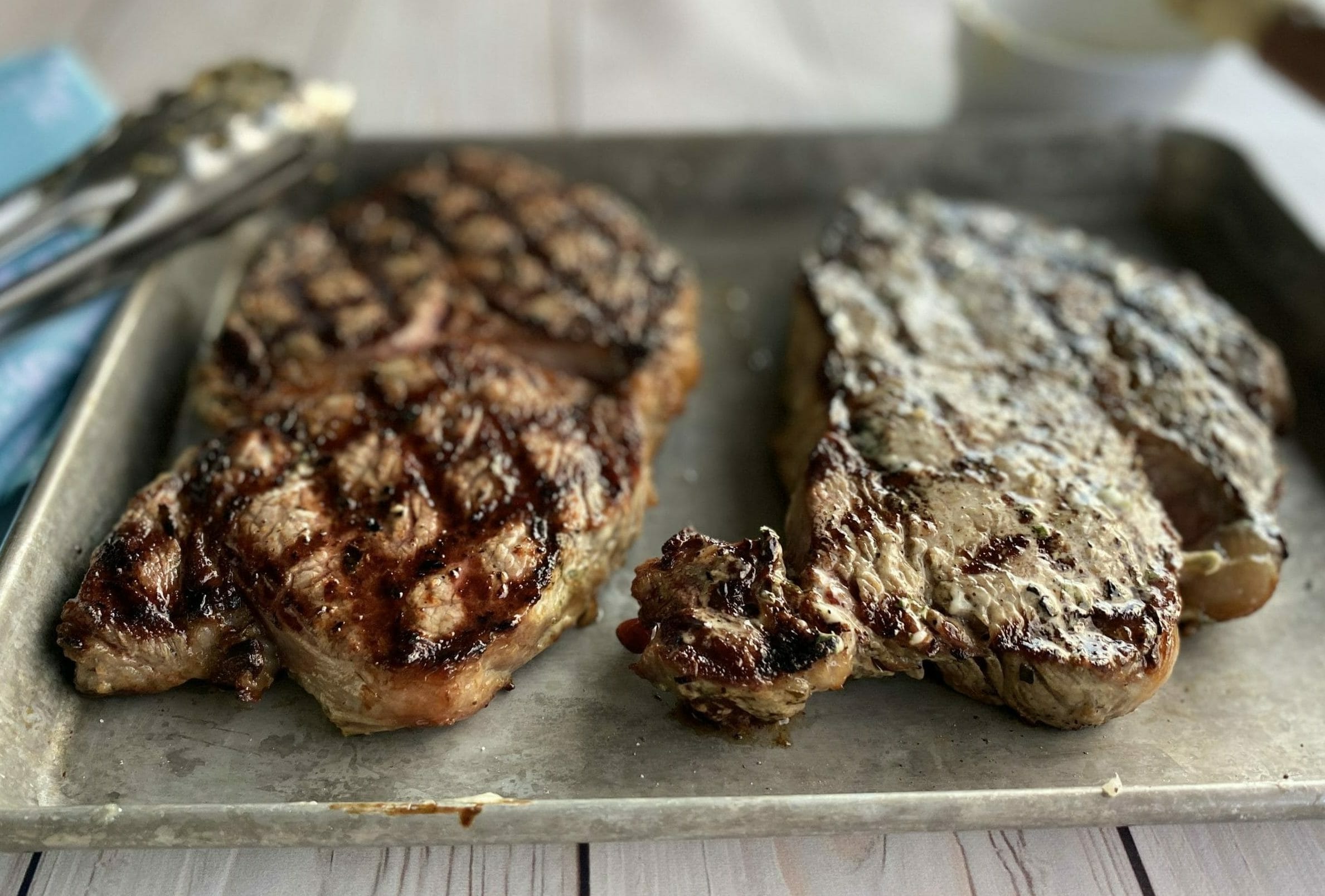 Two Perfectly Grilled Ribeye Steaks topped with Tarragon Mayo, on a serving plate