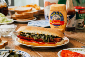 Cajun Sausage, Lettuce and Tomato sandwich on po-boy bread dressed with cooked collard greens and Blue Plate Hot & Spicy Mayonnaise.