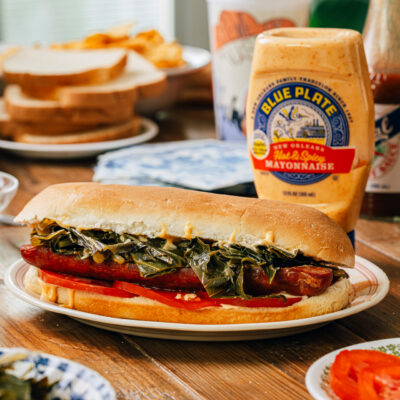 Cajun Sausage, Lettuce and Tomato sandwich on po-boy bread dressed with cooked collard greens and Blue Plate Hot & Spicy Mayonnaise.