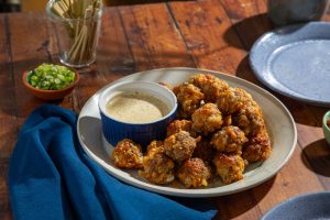 cheesy sausage balls with dipping sauce on serving plate
