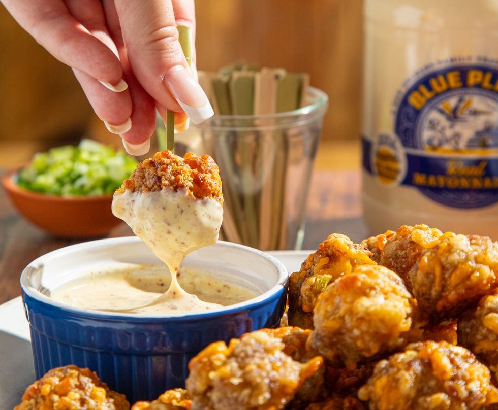 cheesy sausage balls being dipped into honey creole mustard sauce